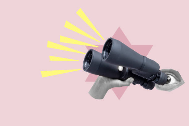 A human hand holding the binoculars on a colored background. Collage art A human hand holding the binoculars on a colored background. Collage art